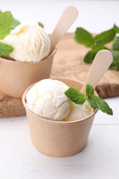 Photo of Delicious vanilla ice cream and mint on white wooden table
