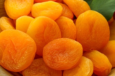 Photo of Tasty dried apricots and leaf as background, closeup