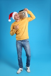 Photo of Emotional man with vintage radio on blue background. Christmas music