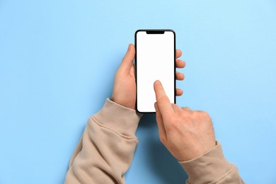 Photo of Man using smartphone on light blue background, top view. Space for text