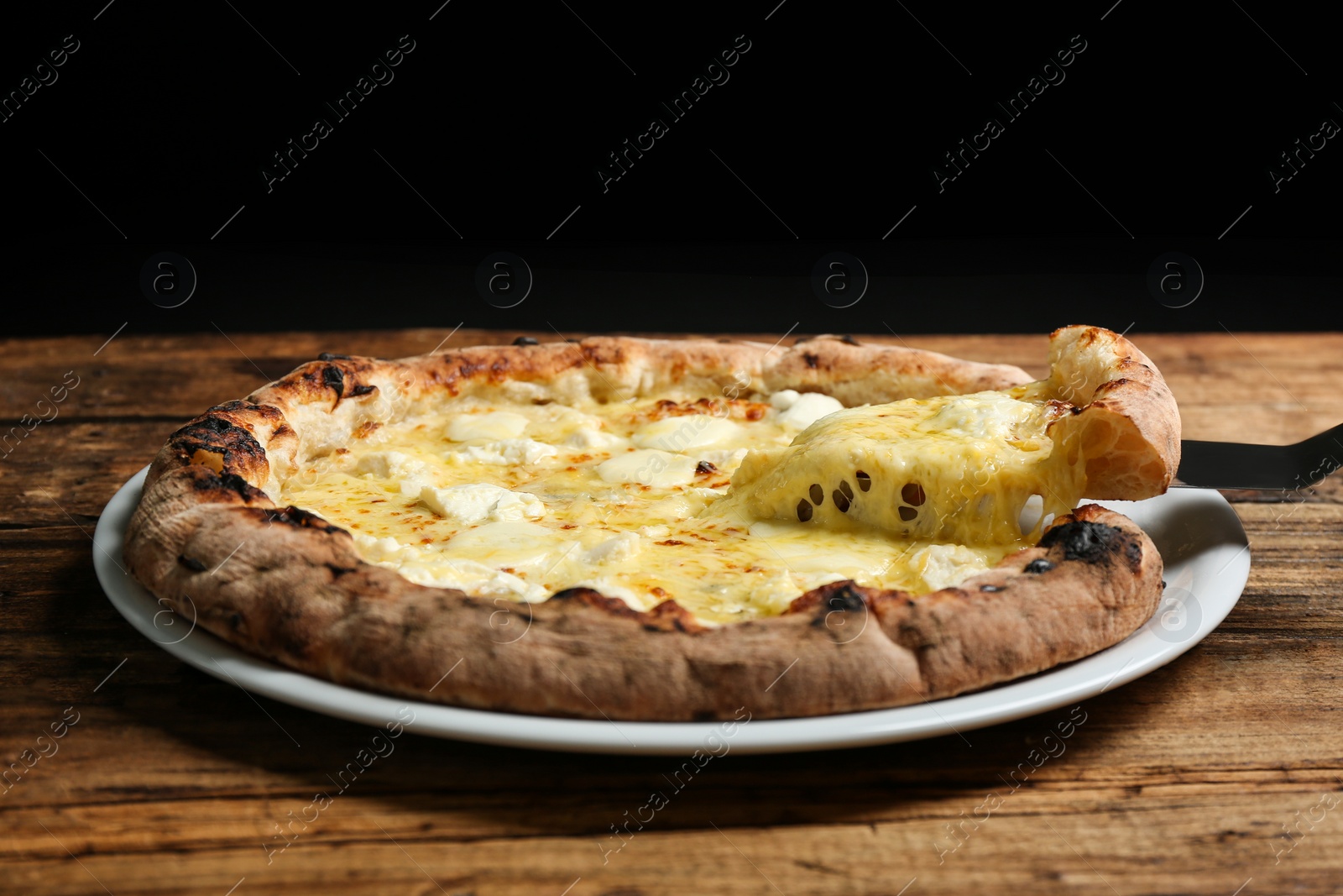 Photo of Taking slice of tasty cheese pizza on wooden table, closeup