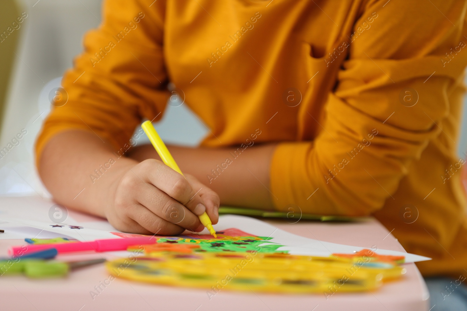 Photo of Little child drawing at table indoors, closeup. Christmas season