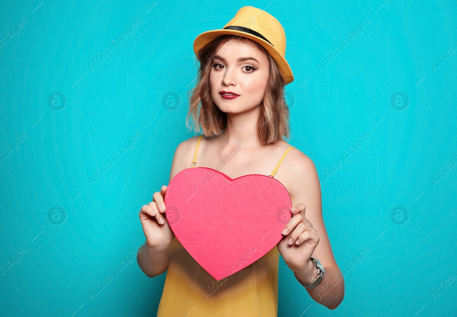Photo of Beautiful young woman with pink heart posing on color background