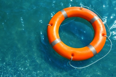 Photo of Orange life buoy floating in sea, above view. Emergency rescue equipment