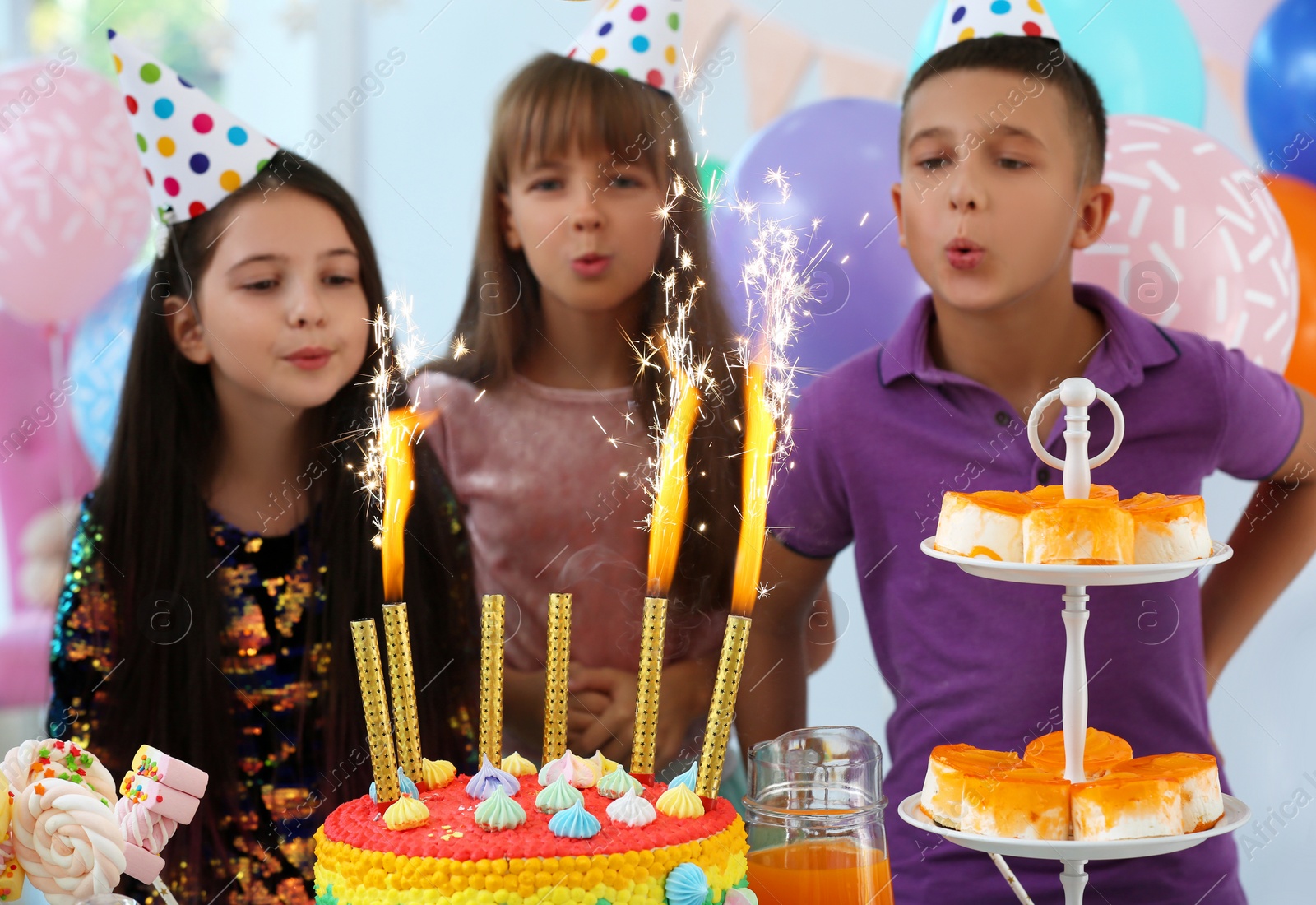 Photo of Happy children near cake with firework candles at birthday party indoors