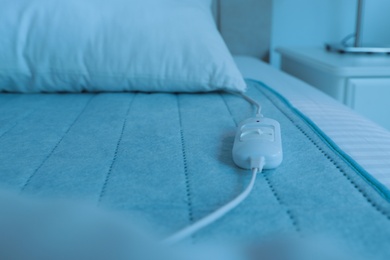 Photo of Bed with electric heating pad indoors, closeup