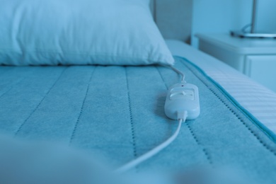 Bed with electric heating pad indoors, closeup