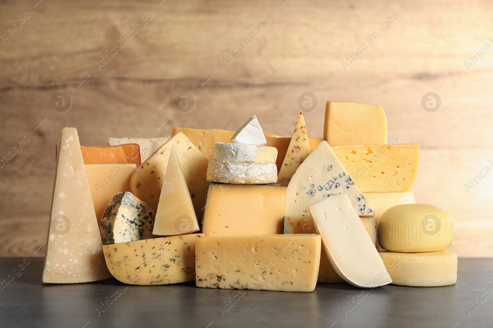 Photo of Different types of delicious cheese on table against wooden background