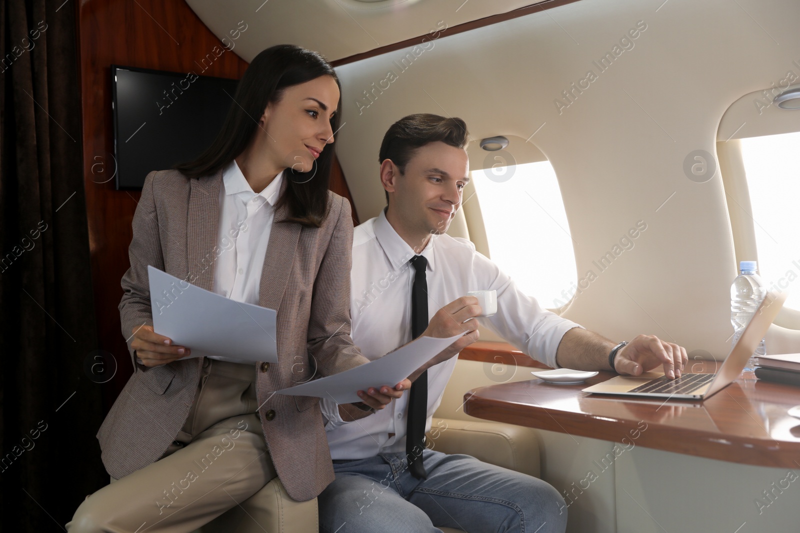 Photo of Colleagues working together in airplane during flight