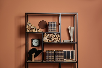 Photo of Stylish shelving unit with decorative elements near color wall. Interior design