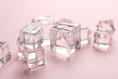 Photo of Crystal clear ice cubes on pink background, closeup