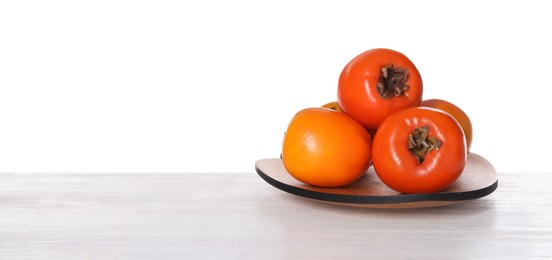 Photo of Delicious ripe juicy persimmons in plate on wooden table against white background