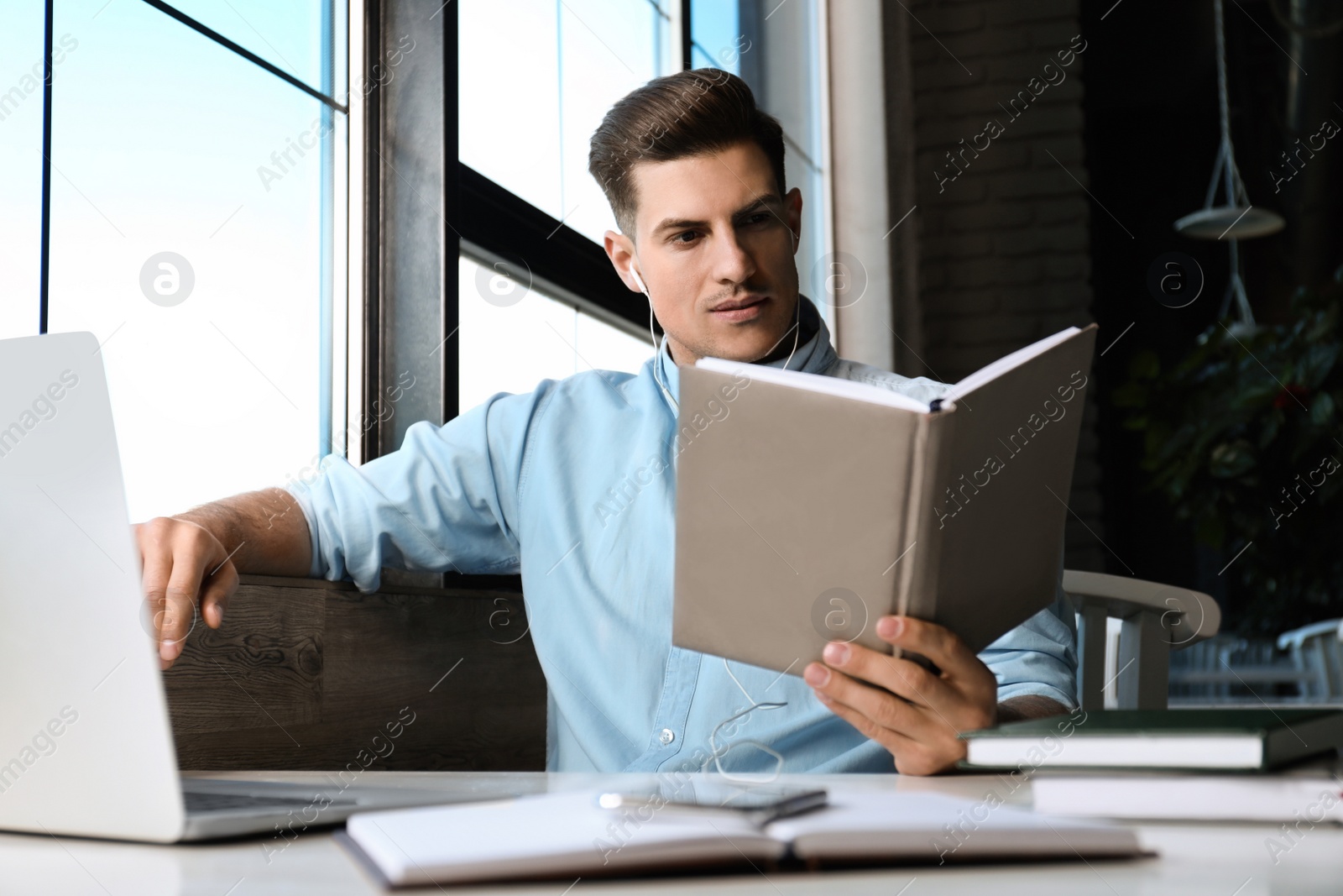 Photo of Man listening to audiobook at table in cafe