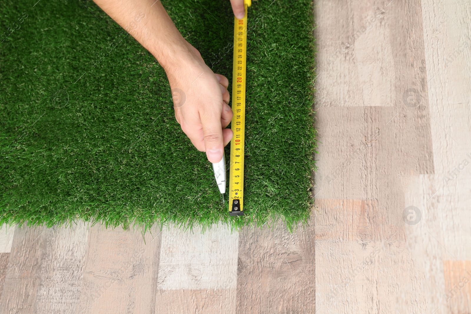 Photo of Man cutting artificial grass carpet indoors, top view. Space for text