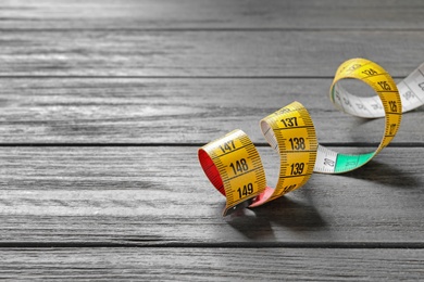 Measuring tape on wooden background. Tailoring equipment