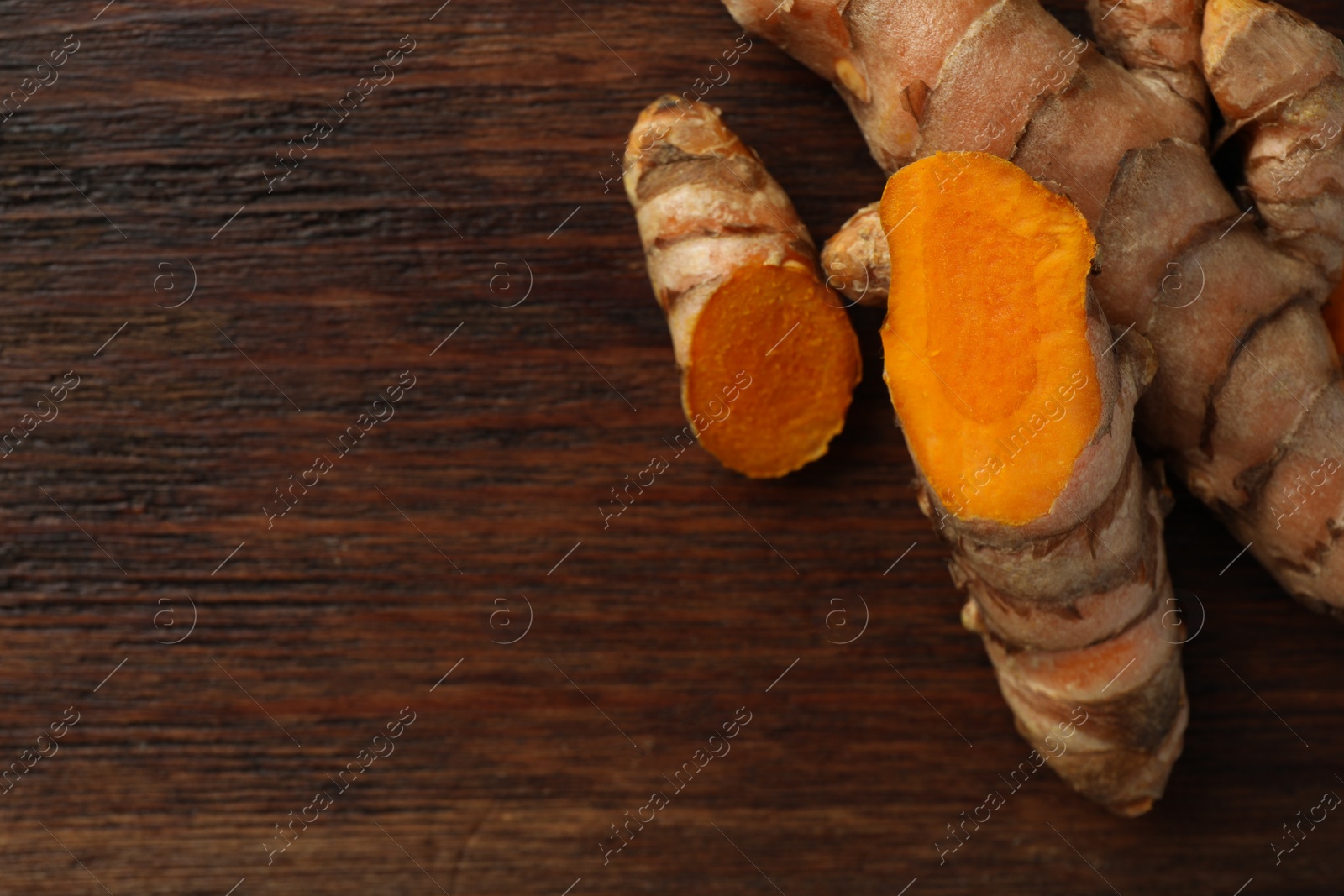 Photo of Fresh turmeric roots on wooden table, flat lay. Space for text