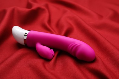 Pink vibrator on red fabric. Sex toy