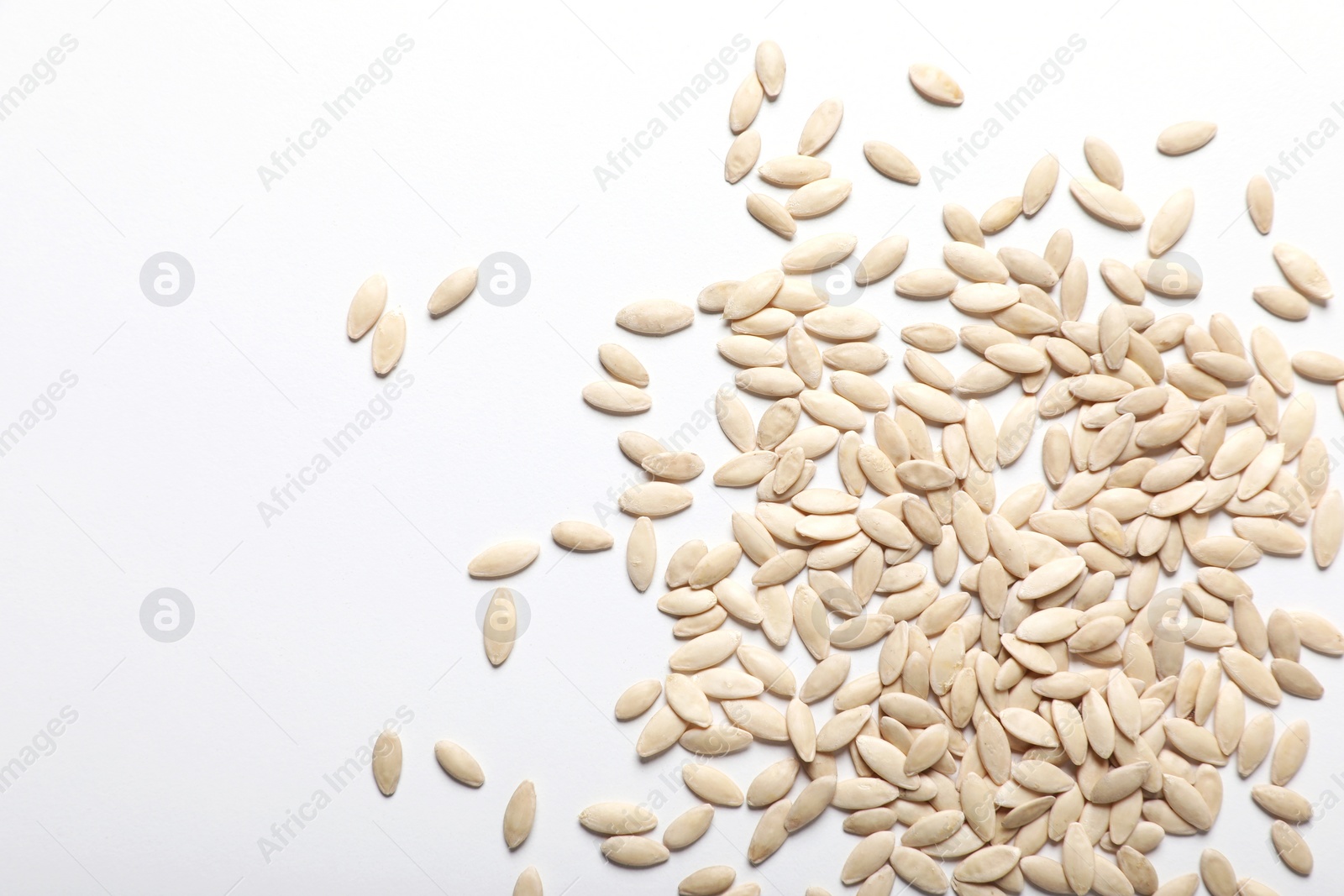 Photo of Pile of cucumber seeds on white background, top view