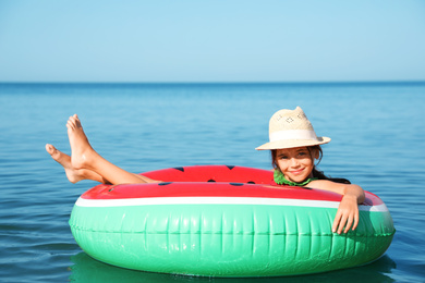 Photo of Cute little child with inflatable ring in sea on sunny day. Beach holiday