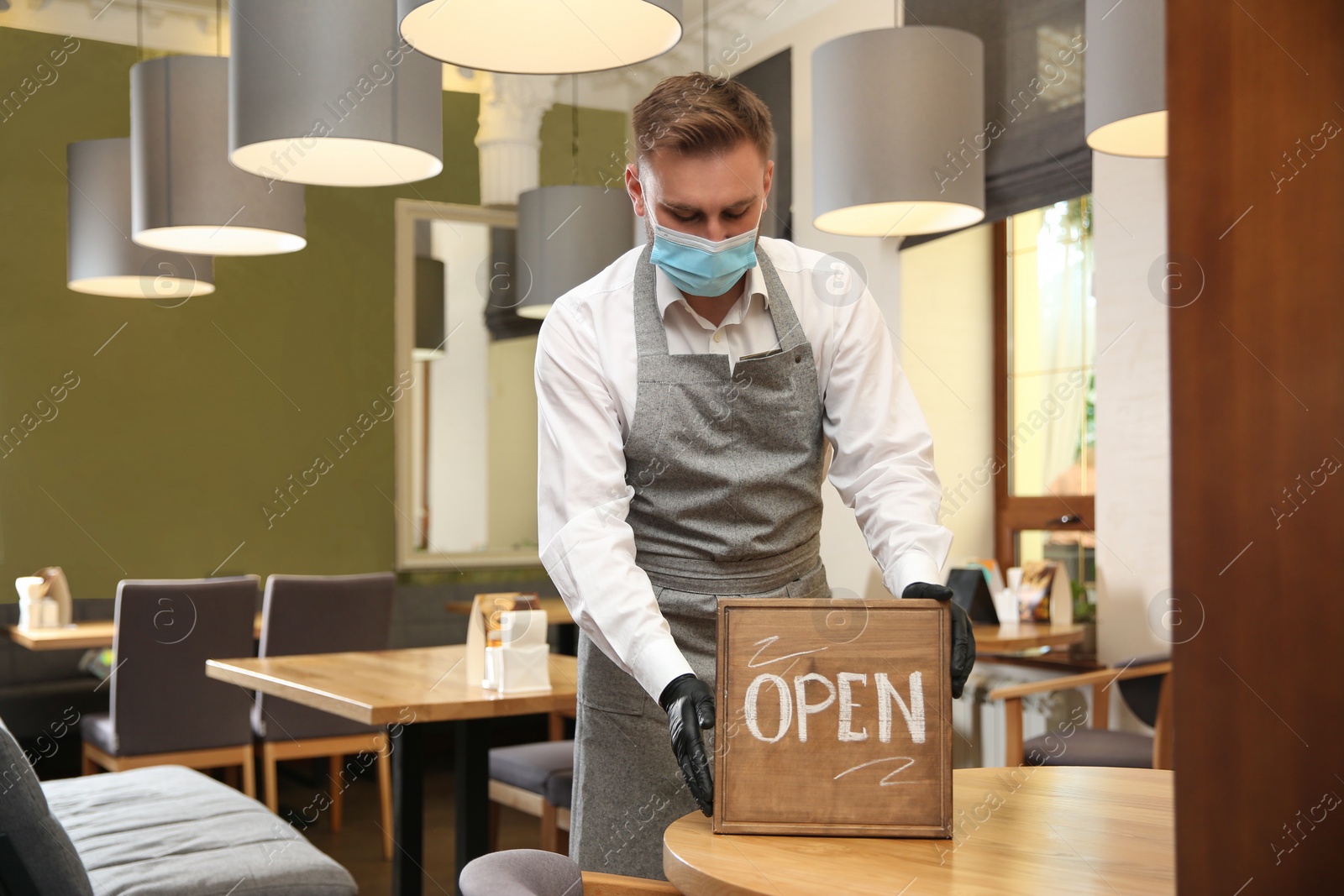 Photo of Waiter with OPEN sign in restaurant. Catering service during coronavirus quarantine