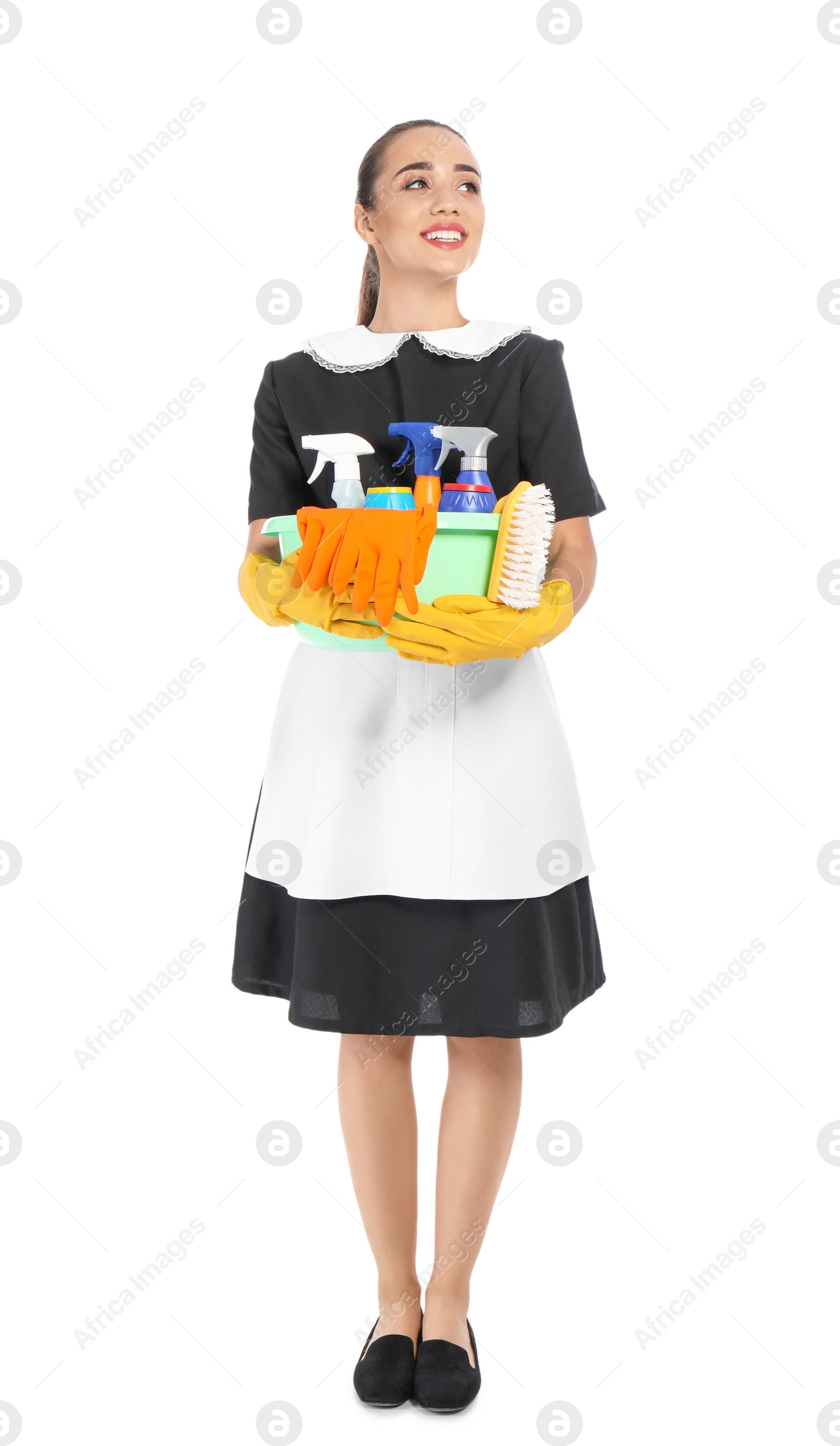 Photo of Young chambermaid holding plastic basin with detergents on white background