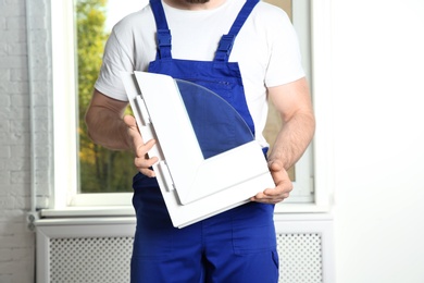 Photo of Installation worker with sample of modern window profile indoors