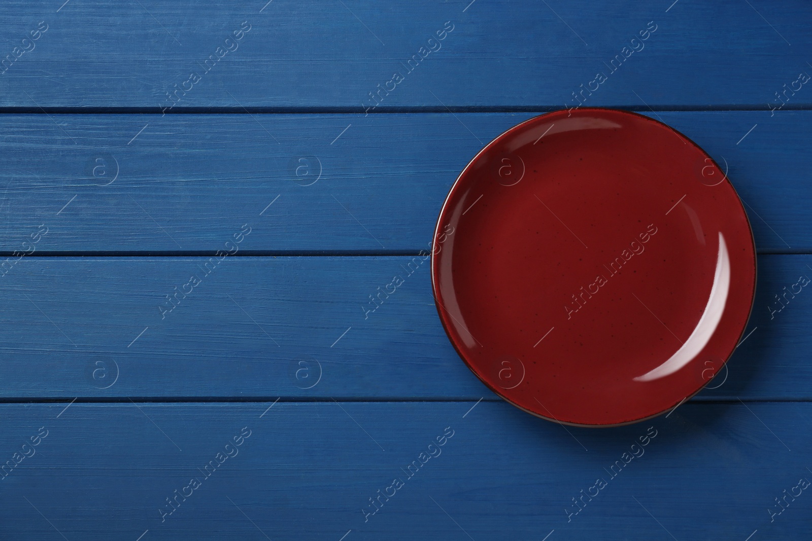 Photo of Clean plate on wooden blue table, top view. Space for text