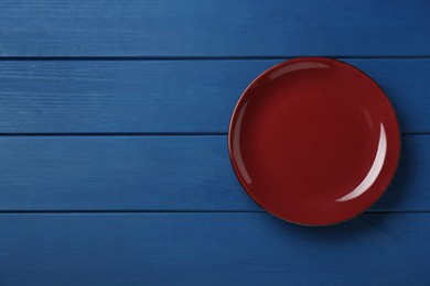 Photo of Clean plate on wooden blue table, top view. Space for text