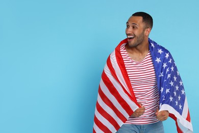 Photo of 4th of July - Independence Day of USA. Happy man with American flag on light blue background, space for text