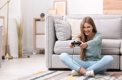 Emotional young woman playing video games at home