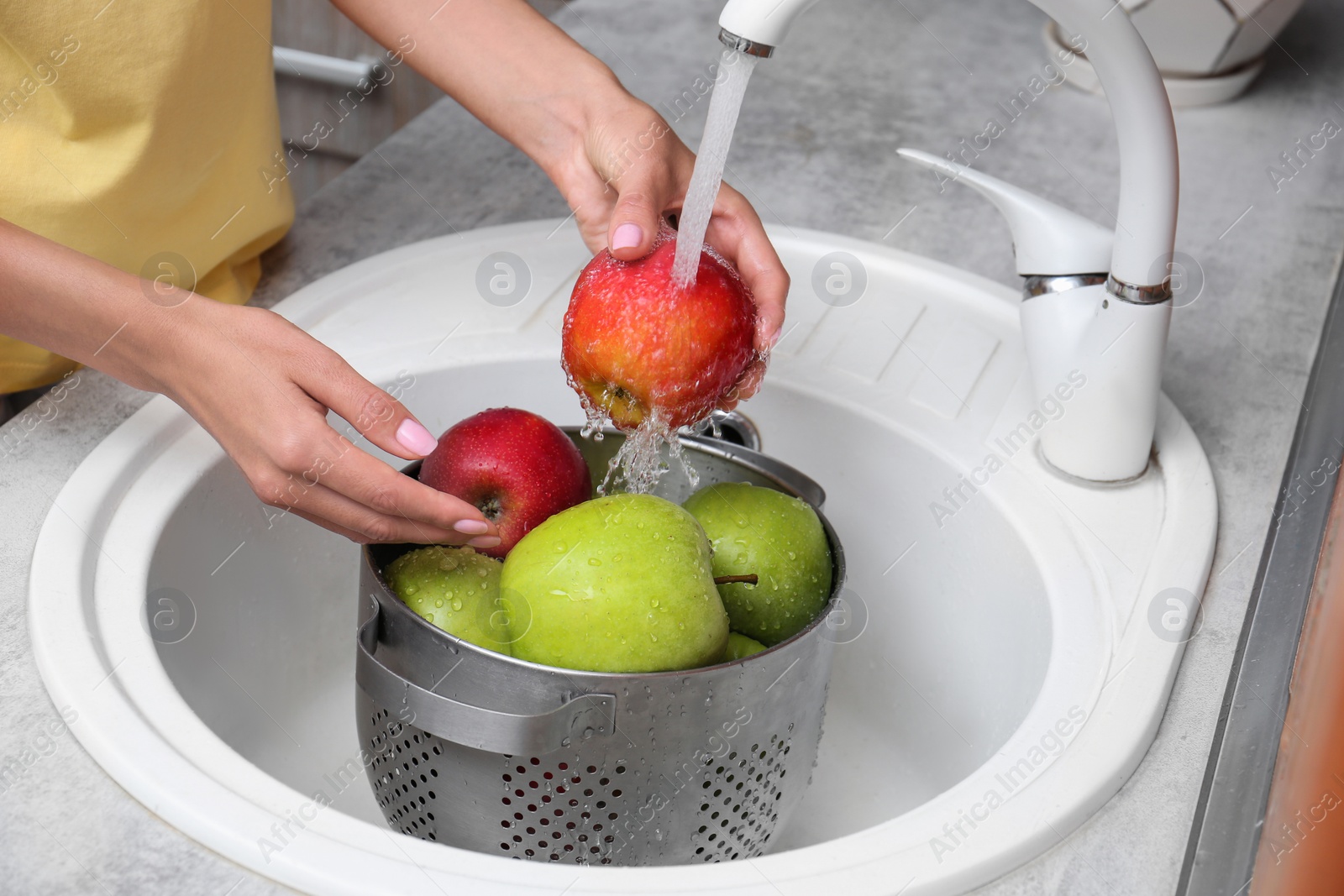 Photo of Woman washing fresh apples in kitchen sink, closeup