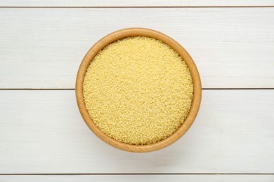 Bowl of raw couscous on white wooden table, top view