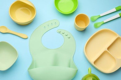 Photo of Flat lay composition with baby feeding accessories and bib on light blue background