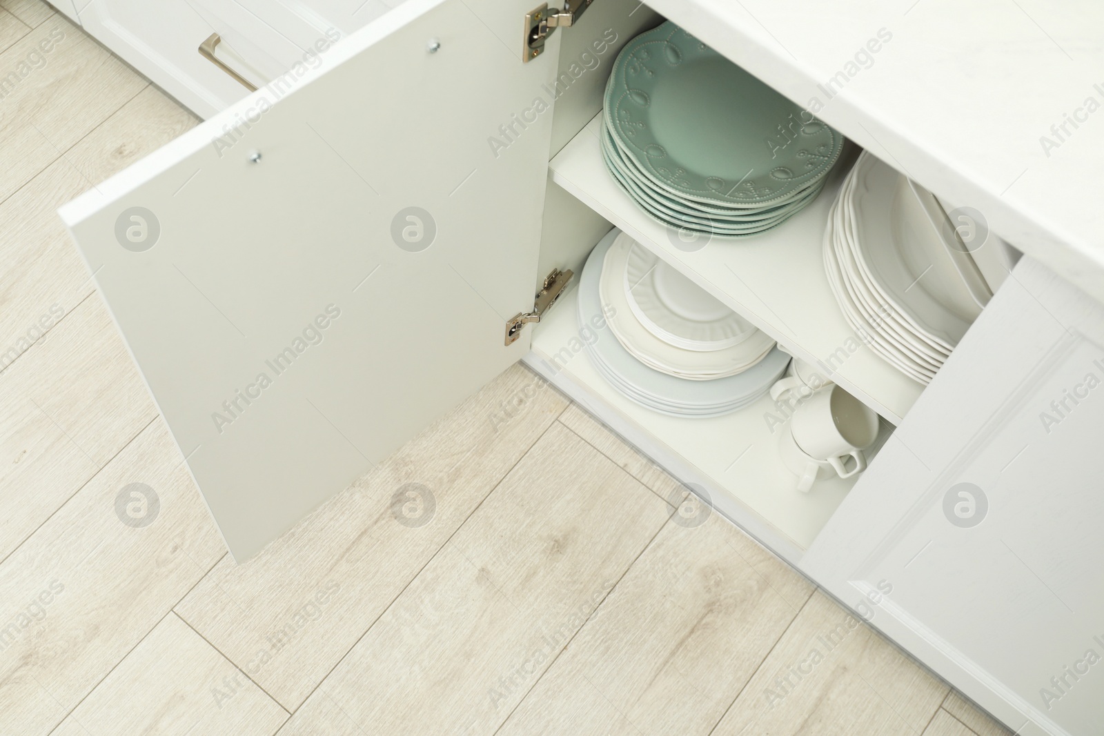 Photo of Clean plates and cups on shelves in cabinet indoors