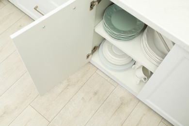 Clean plates and cups on shelves in cabinet indoors