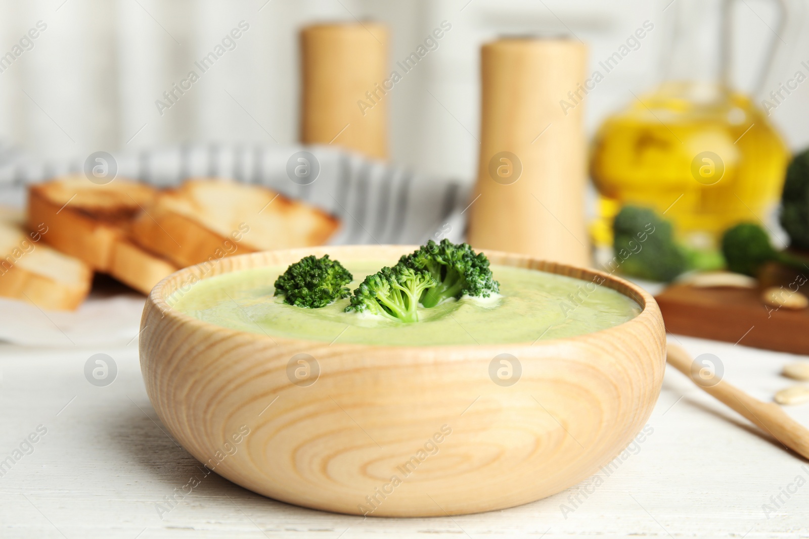 Photo of Delicious broccoli cream soup served on white wooden table