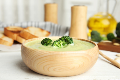 Photo of Delicious broccoli cream soup served on white wooden table