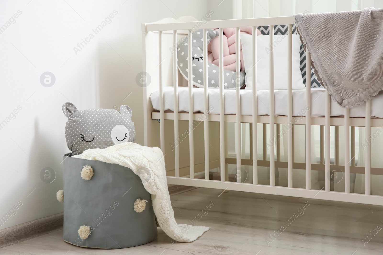 Photo of Basket with toy near crib in baby room. Interior design