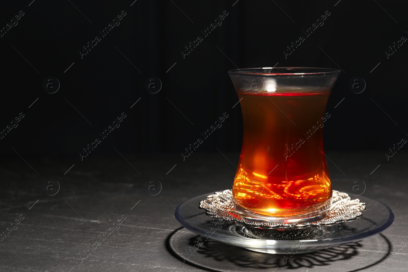 Photo of Glass with traditional Turkish tea on black table. Space for text