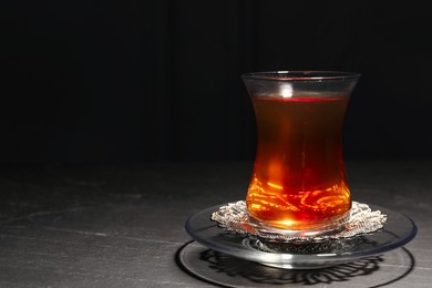 Photo of Glass with traditional Turkish tea on black table. Space for text