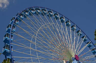 Photo of Amusement park. Beautiful Ferris wheel against blue sky, low angle view