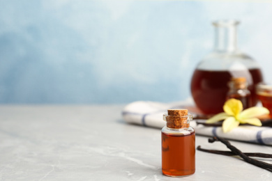 Photo of Aromatic homemade vanilla extract on light grey marble table. Space for text