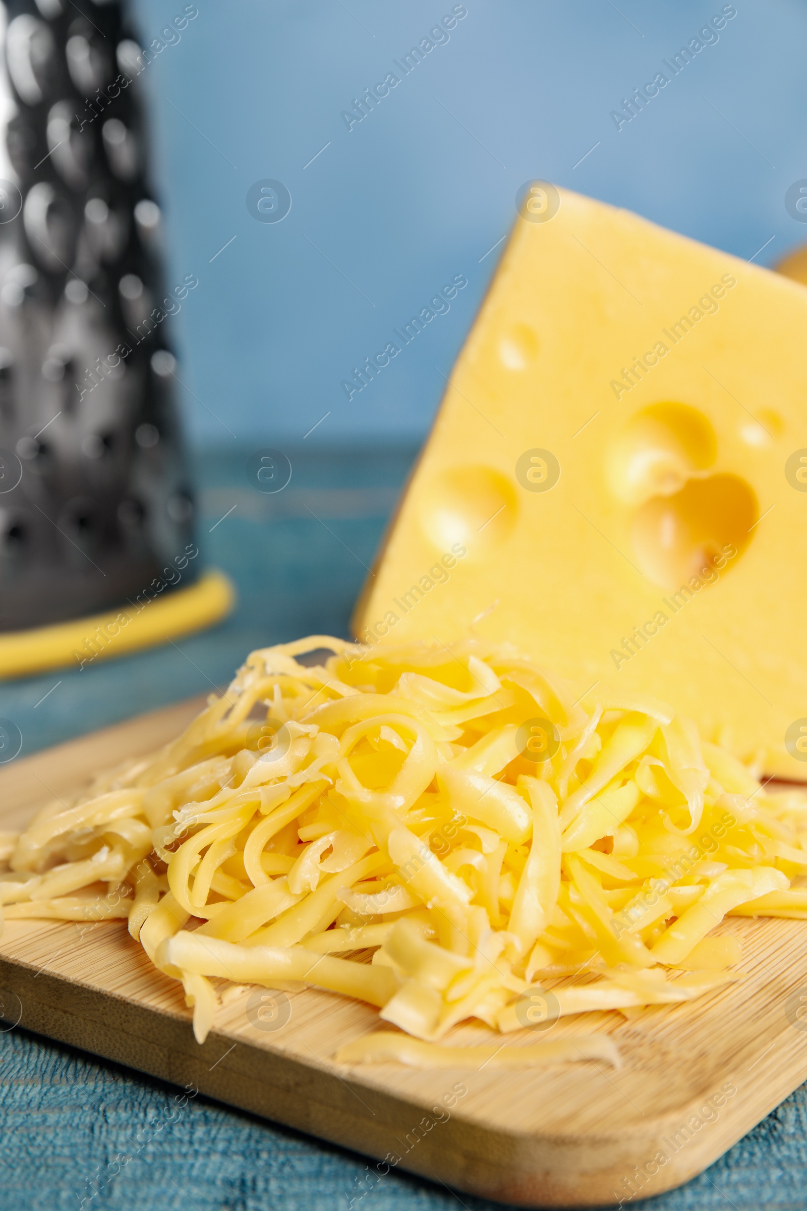 Photo of Tasty grated cheese on blue wooden table