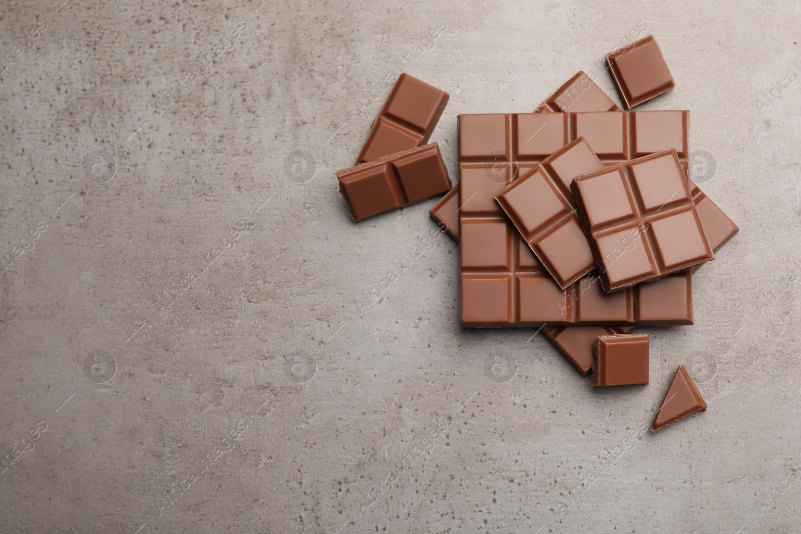 Photo of Delicious milk chocolate on light grey table, flat lay. Space for text