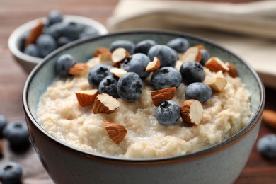 Photo of Tasty oatmeal porridge with blueberries and almond nuts on table, closeup