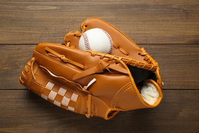 Photo of Leather baseball glove with ball on wooden table, top view