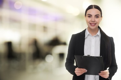 Lawyer, consultant, business owner. Confident woman with clipboard smiling indoors, space for text