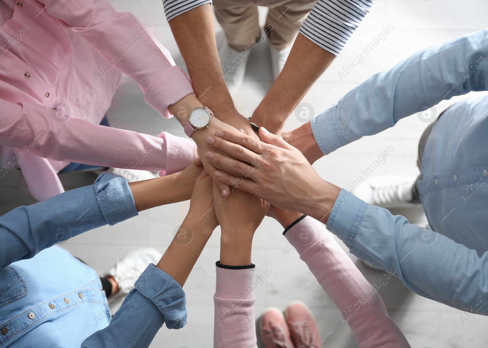People holding hands together over light background, top view. Unity concept Photo of People holding hands together over light background, top view. Unity concept