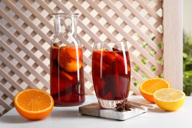 Photo of Aromatic punch drink and ingredients on white table