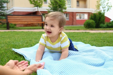 Adorable little baby crawling towards mother on blanket outdoors